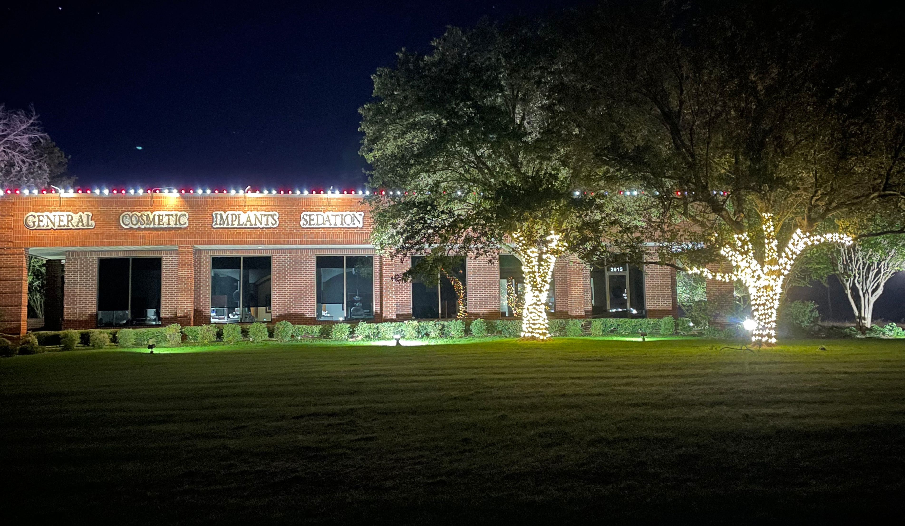 Dental office with holiday lights on roofline and fully wrapped trees