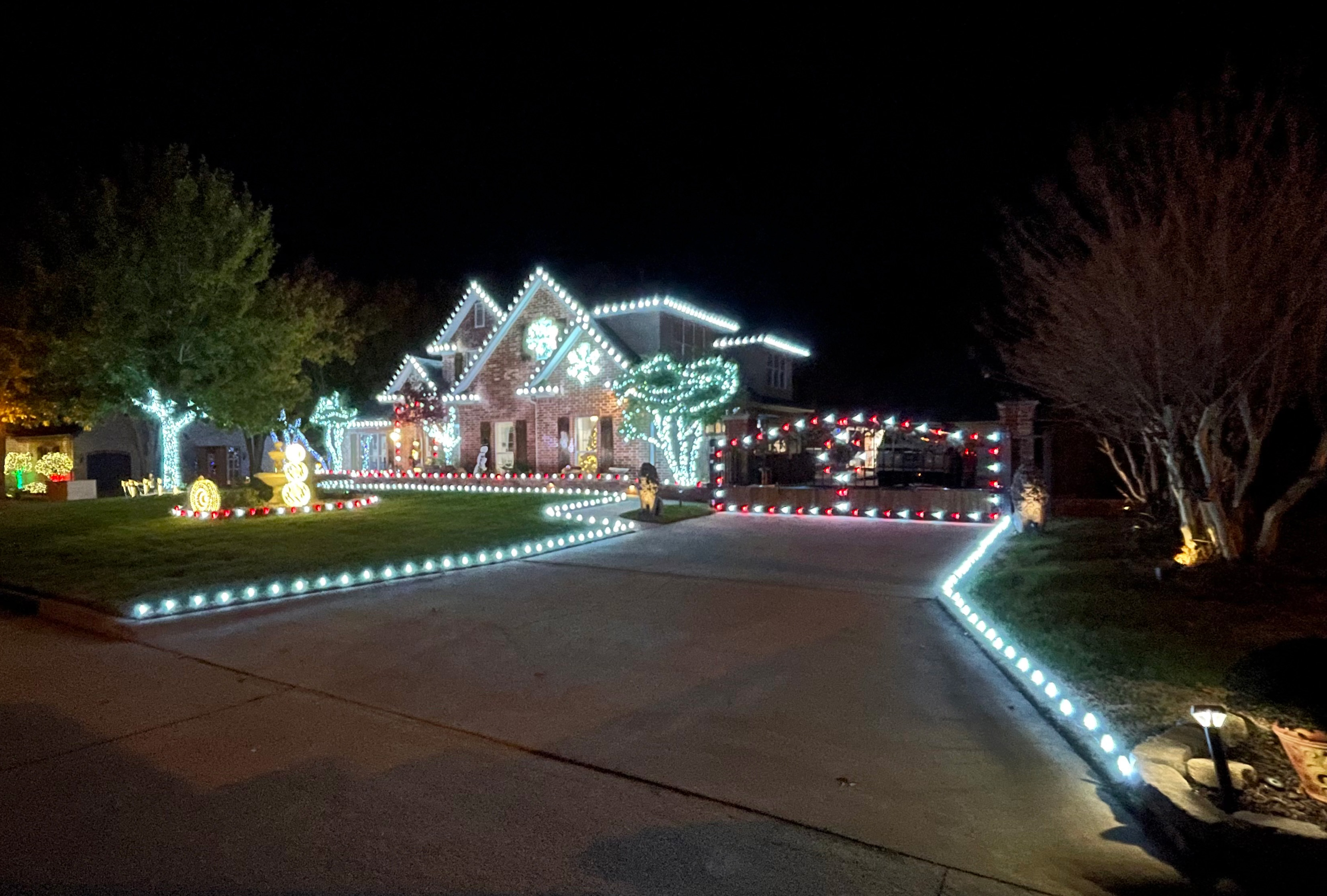 Deluxe full-property Christmas lighting install with lights lining the roofline, driveway, and yard