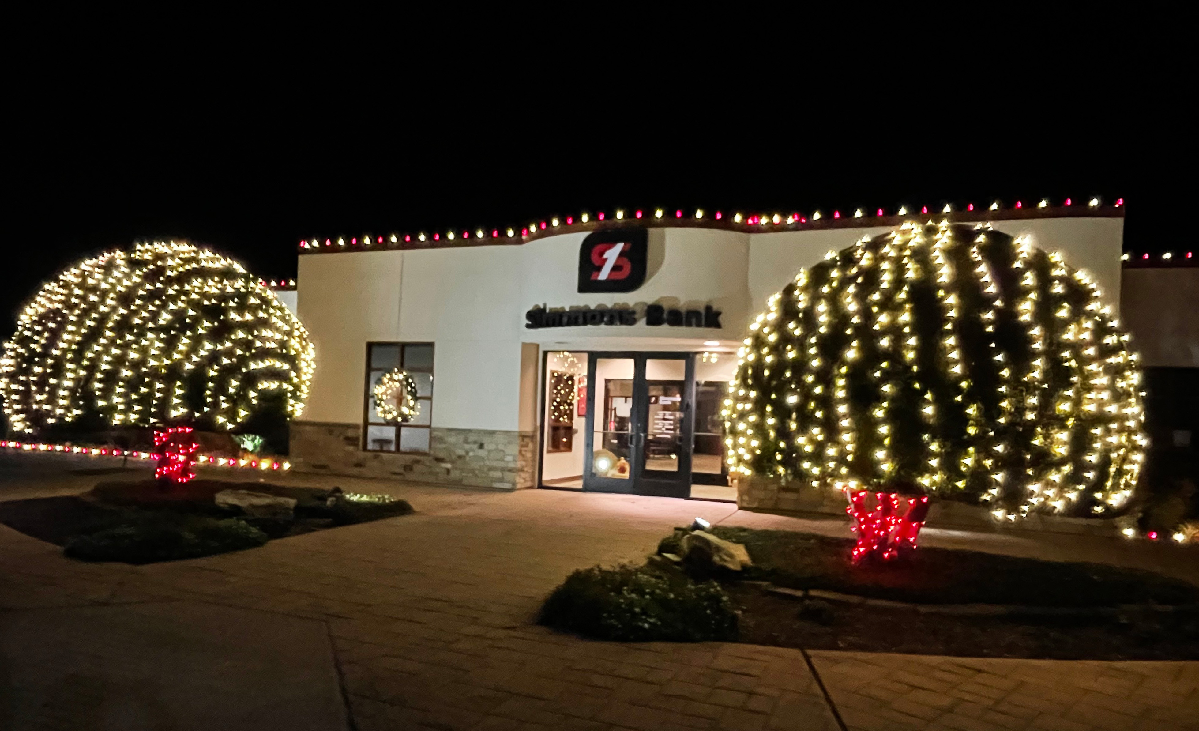 Simmons Bank commercial holiday display with large globe-wrapped shrubs and roofline lights